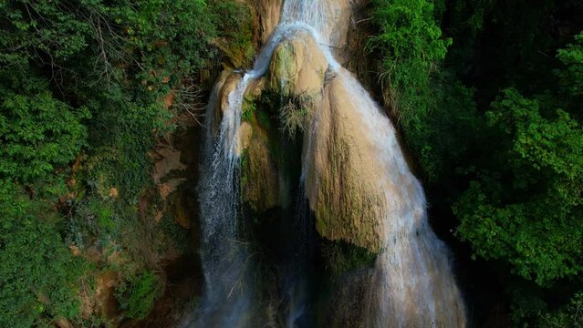 Drones fly over Tad Mok Waterfall during sunlight, Water flows over the stones. beautiful waterfall in tropical forest. Natural the texture for background. Lampang, Northern Thailand. 4K
