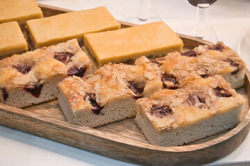 Wooden tray with different sorts of cake on it. Small pieces of cake served on a wooden tray. Selection of fruit cake ready to be served. Delicious, tasty, fluffy, flat biscuit cake with cherries. 