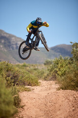 Plakat Bike, bmx and fitness with a man biker on a dirt trail or track taking a jump with a mountain bike. Sky, nature and cycling with a mountain biker jumping in midair while riding outdoor for adrenaline