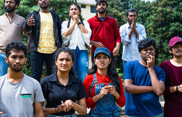 Serious tensed audience watching cricket sports match at stadiumby biting nails and praying god - concept of entertainment, championship and hopeful