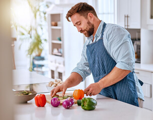 Man, chef and cooking, cut vegetable in kitchen and healthy with diet, nutrition and vitamins preparing dinner or lunch meal. Food at home with apron and organic, fresh pepper and onion.