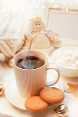  Winter, Christmas, New Year decorations composition, concept, background. White Mug, cup of hot tea, coffee, meringue, knitted plaid. Christmas lights. Christmas mood morning. Christmas card.