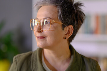 Profile portrait of middle aged mature grey haired woman. Close up of attractive happy woman in glasses looking beside. Portrait of positive single senior female.