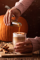 Woman hand holding homemade pumpkin spice latte made from scratch with pumpkin spice syrup
