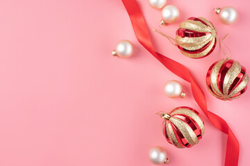 minimal christmas background with balls and red ribbon on pink background, flat lay