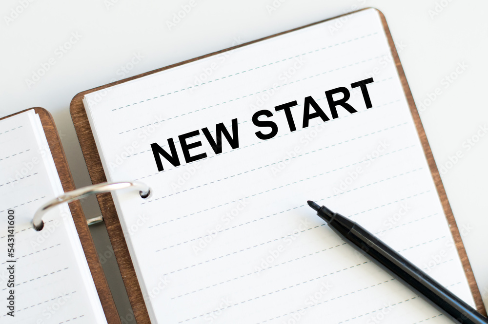 Poster new start text on notepad on the table next to the black marker