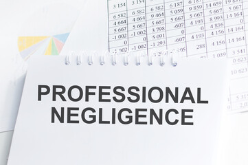 Notebook with the text PROFESSIONAL NEGLIGENCE on the office table among the stationery.