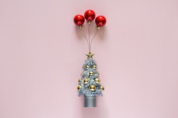 Christmas tree with red baubles ornament set as ballon on top with pink background. Minimal holiday concept.