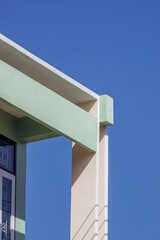 Sunlight on surface of rectangle pillar and shading fin concrete with roof awning on green and beige vintage house against blue clear sky in vertical frame