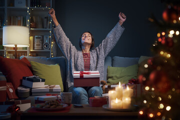 Cheerful woman opening Christmas gifts