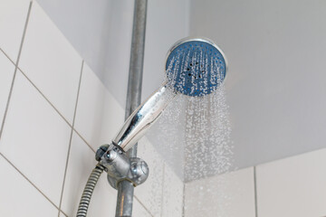 Running cold water from a shower head in a bathroom.