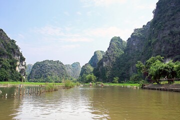 Fototapeta na wymiar Tourists traveling in boat along the Ngo Dong River, Landscape formed by karst towers and rice fields, in Ninh Binh - Vietnam