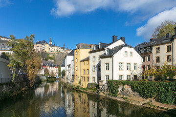 Fototapeta na wymiar Luxembourg City Grund with Pétrusse River in the sunshine with blue sky and clouds.