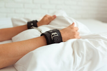 Female hands in black handcuffs, sex toys
