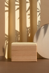 Geometric wooden podium on an abstract beige background with a shadow of palm leaves. A scene with...