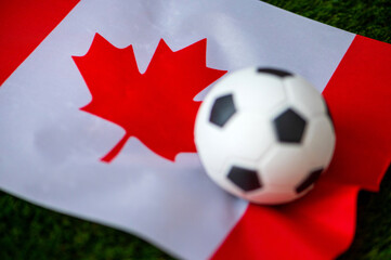 Canada national football team. National Flag on green grass and soccer ball. Football wallpaper for Championship and Tournament in 2022. World international match.
