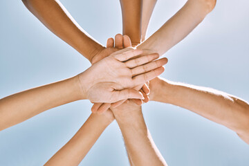 Below hands stack, group motivation support and trust together outdoor with blue sky. Team hand...