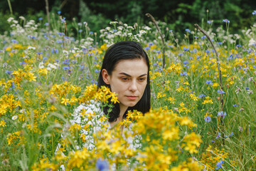 Beautiful girl among the summer field with wildflowers