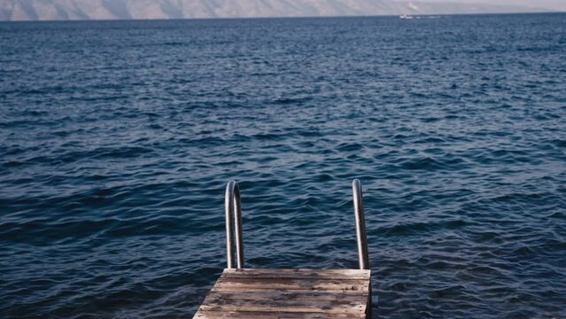 Old school ladder confronting blue crystal clear sea
