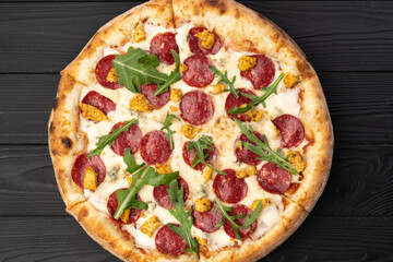 Homemade fresh Pizza with salami, cherry tomatoes and arugula on a black wooden. Copy space. Top view food photo. Flat lay. Italian cuisine