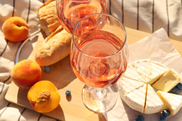 Glasses of delicious rose wine and food on white picnic blanket