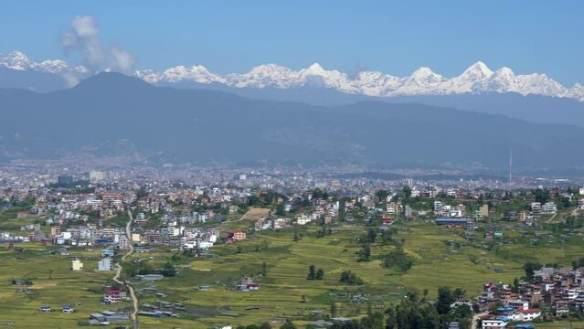 A panning view of the city of Kathmandu, Nepal on a sunny day with the Himalaya Mountains in the background.