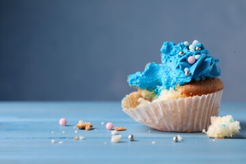Failed cupcake on blue wooden table, closeup. Troubles happen