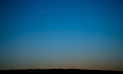 Mountain silhouette with communication antenna and plane trails