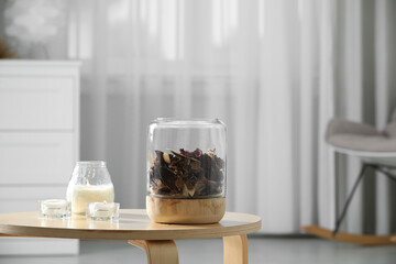 Decorative jar with aromatic potpourri and candles on wooden table in room, space for text
