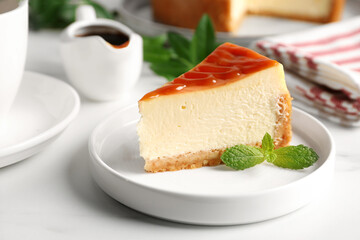 Piece of delicious caramel cheesecake served on white marble table, closeup
