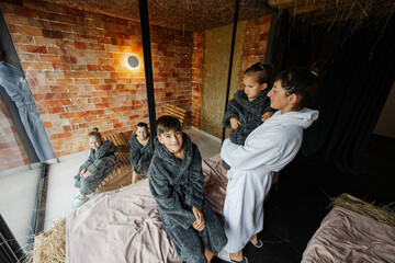 Mother with kids in bath robe relaxing in the salt room with hay.