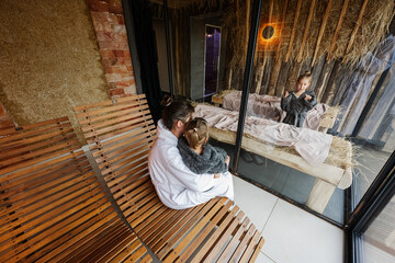 Mother with daughters in bath robe relaxing in the salt room with hay.