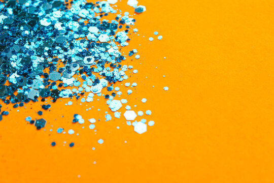 Shiny Bright Light Blue Glitter On Orange Background. Space For Text