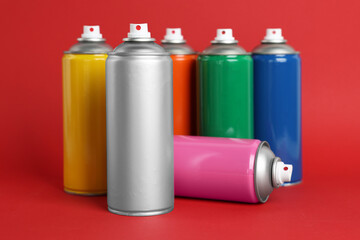 Colorful cans of spray paints on red background