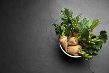 Colander with fresh sugar beets on black table, top view. Space for text