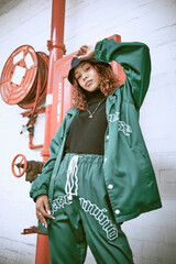 Fashion, wall and black woman with green clothes, fashionable style or cool hip hop outfit. Fire hose, attitude or portrait of gen z girl with trendy streetwear, designer brand or 2000s rap aesthetic