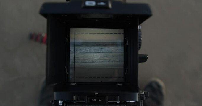 Waves crashing on the beach through the viewfinder of a film camera