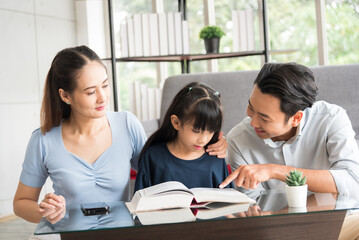 Happy family sitting together and help teaching daughter about her homework in living room.