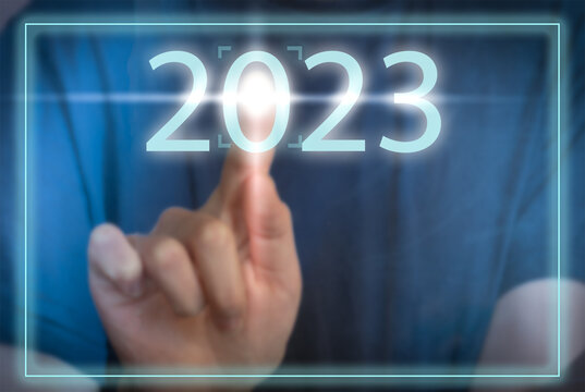 Finger pressing  2023 button on virtual interface on blue background with copy space for text. Concept of new year.