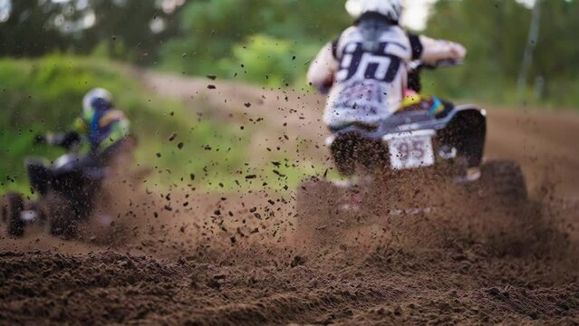 Quad Bikers Racing Competition on Dirt Muddy Road With Mud Scattering Under Wheels in Slow motion