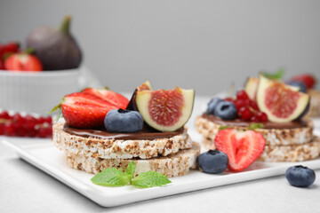 Tasty crispbreads with chocolate, figs and berries served on light table