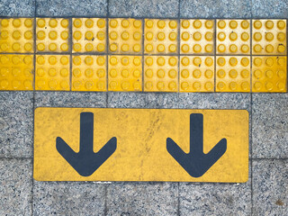 Yellow guiding block brick floor pattern with arrow sign in the train station