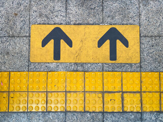 Yellow guiding block brick floor pattern with arrow sign in the train station