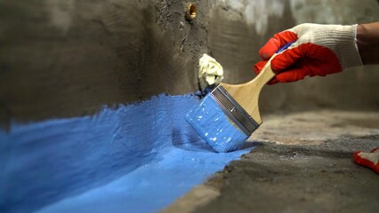 Waterproofing the floor with a brush.Waterproofing concrete mortar. The master puts waterproofing...
