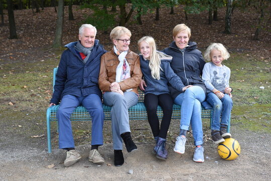 Familie mit Gro&szlig;eltern auf einer Bank im Park