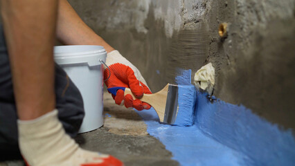 Waterproofing the floor with a brush.Waterproofing concrete mortar. The master puts waterproofing...