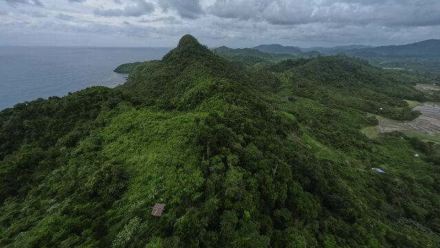Aerial view cinematic mountain ridge greenery dormant volcano tropical beach seascape dramatic sky. FPV sports drone shot flying over picturesque Asian jungle scenery exotic island with sea ocean 4k