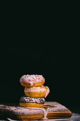 Donuts with chocolate glaze  with sugar powder on the dark background. Pastries concept.