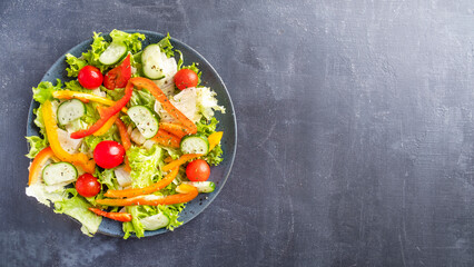 Vegetables salad with pepper, tomato and cucumber on a plate. Top view, text space