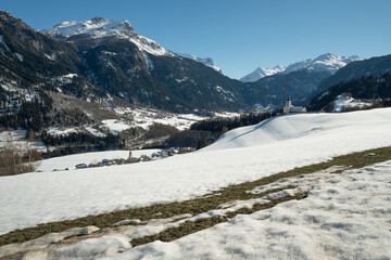The snow begins to melt on a meadow above the village of Donat in the Valley of Schams in the Grisons, Switzerland